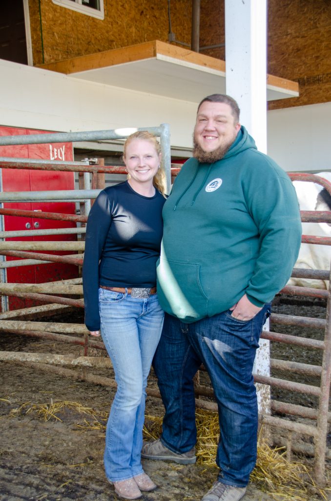 Drew and Beth Rupprecht standing in front of their robotic milker, a component of how they are laying the foundation of the future.